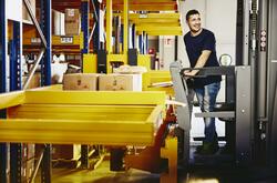 Smiling man standing on a forklift.