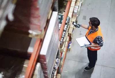 Worker with scanner making review of goods in warehouse