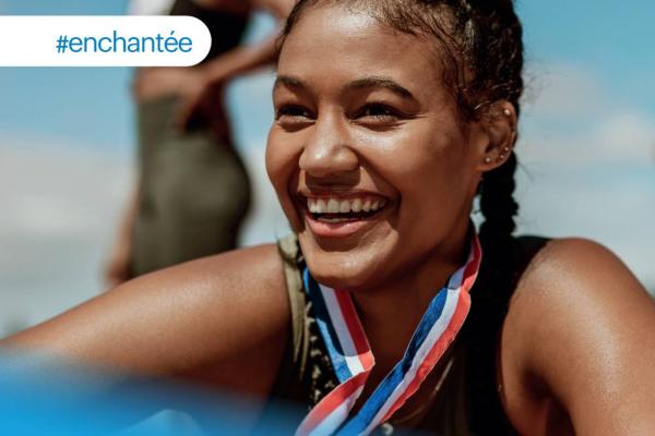 une femme avec une médaille autour du cou sourit